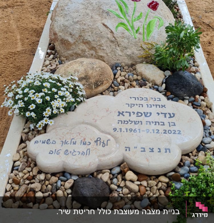 קבר עם אבן גדולה ופרחים צבעוניים